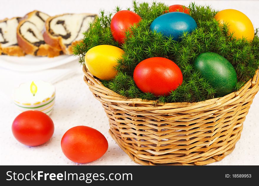 Easter basket with painted eggs and sponge cake in background