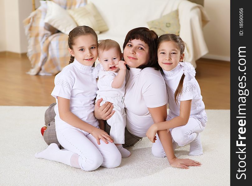 Mother with her three daughters at home on the carpet in the living room. Mother with her three daughters at home on the carpet in the living room