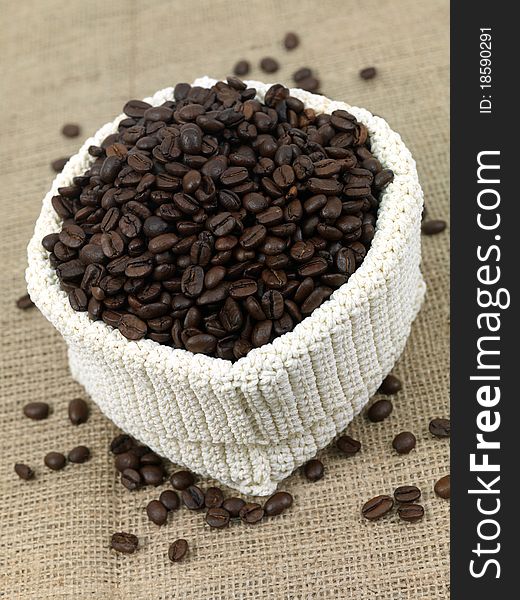 Coffee beans in a woven bag on hessian