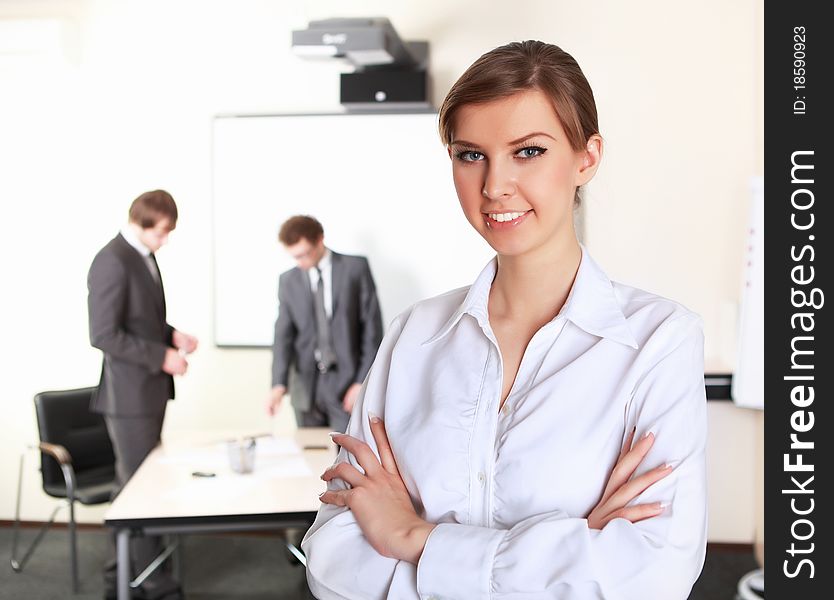 Young and attractive businesswoman in an office with collegues on the background. Young and attractive businesswoman in an office with collegues on the background