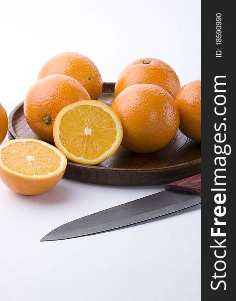 Oranges, wooden tray and a fruit knife on white background