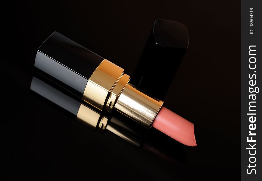 Luxury pink lipstick on black background. make-up accessories