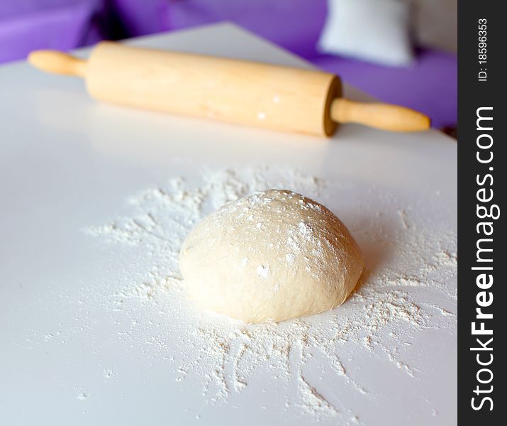 Risen dough from wheat flour for bread making on the kitchen top with the rolling pin. Risen dough from wheat flour for bread making on the kitchen top with the rolling pin.