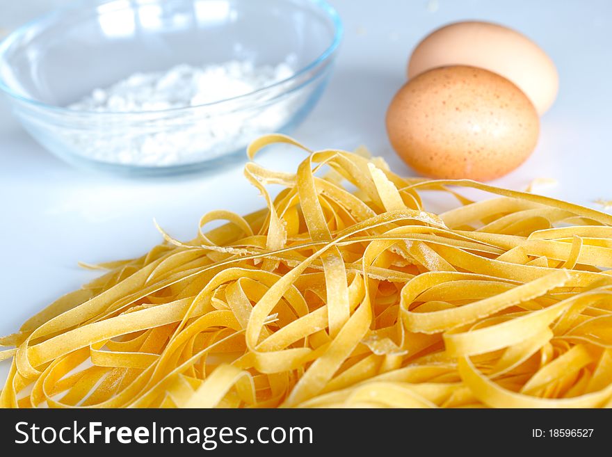 Fresh pasta drying with eggs and flour on white