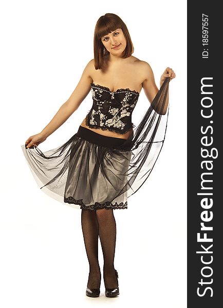 An adult woman poses in a skirt, corset, stockings, shoes on white background isolated