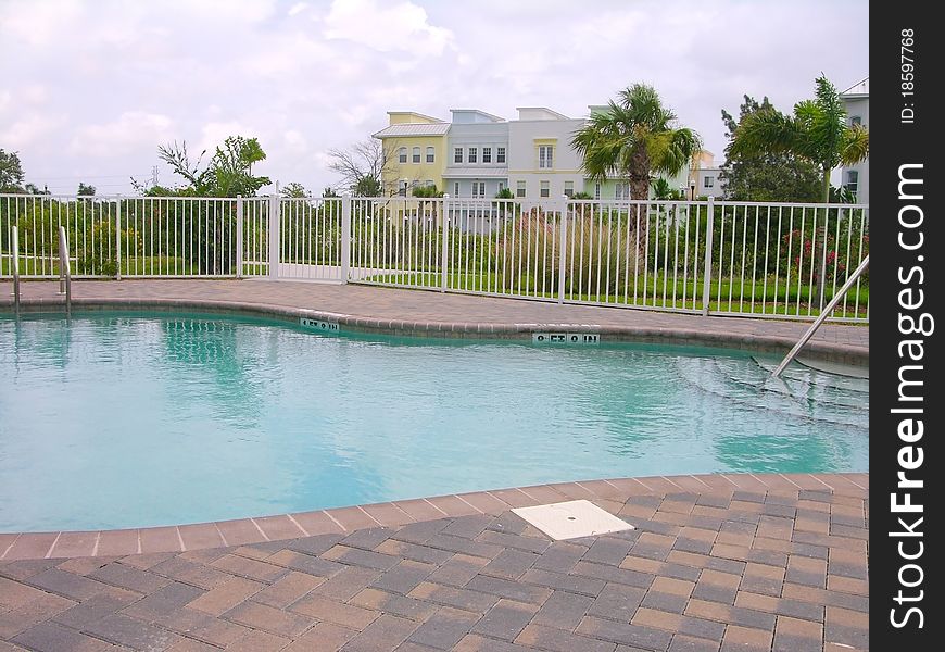 Small clean pool with condo in the background.