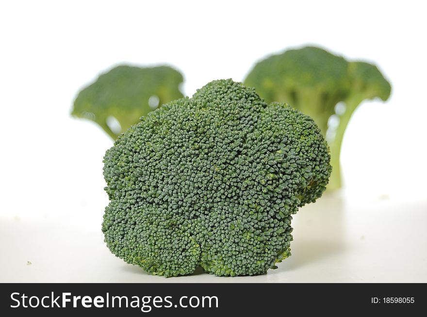 Broccoli vegetable standing on a white shiny table isolated on white background.