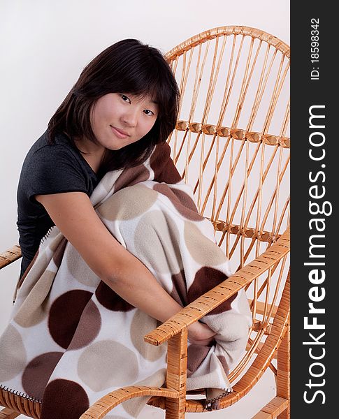 Attractive cheerful  young Asian woman sitting in the rocking-chair. Attractive cheerful  young Asian woman sitting in the rocking-chair