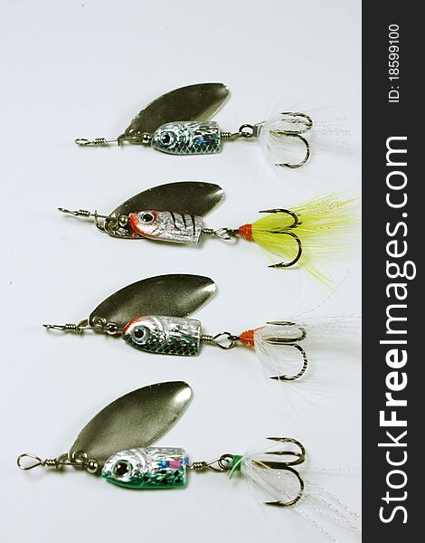 Four fishing lures with treble hooks, feathers and silver spoons