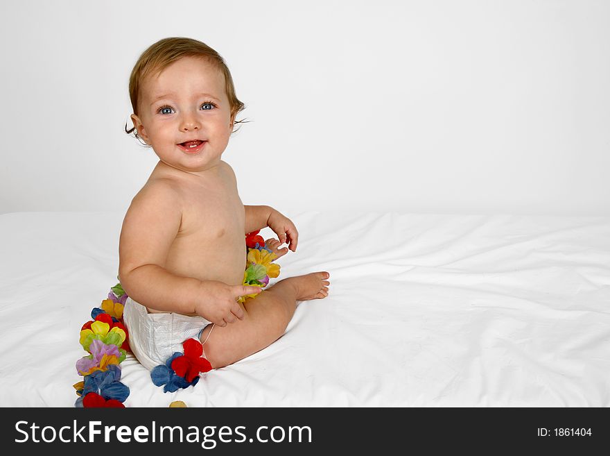 A baby girl sitting with flowers around her. A baby girl sitting with flowers around her