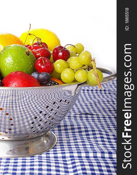 Freshly washed fruits drain in a stainless steel colander.