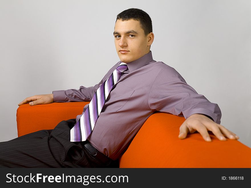 Man's sitting comfortable on the orange couch. Looking at the camera. Man's sitting comfortable on the orange couch. Looking at the camera.