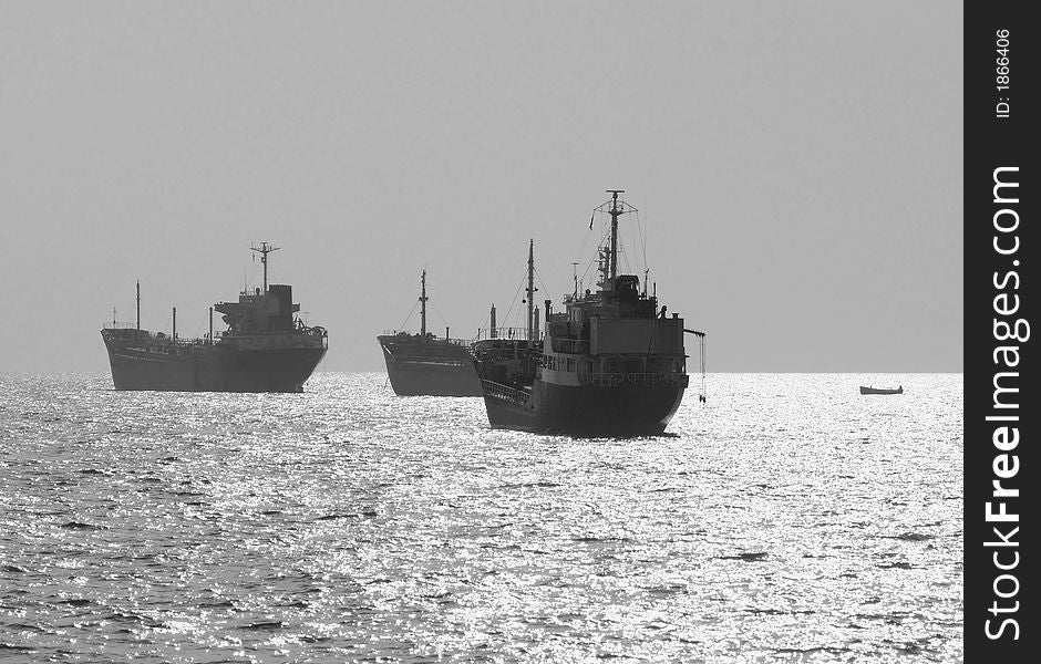 Three small oil tanker at anchor offshore in strong sunlight. Black and white photo.