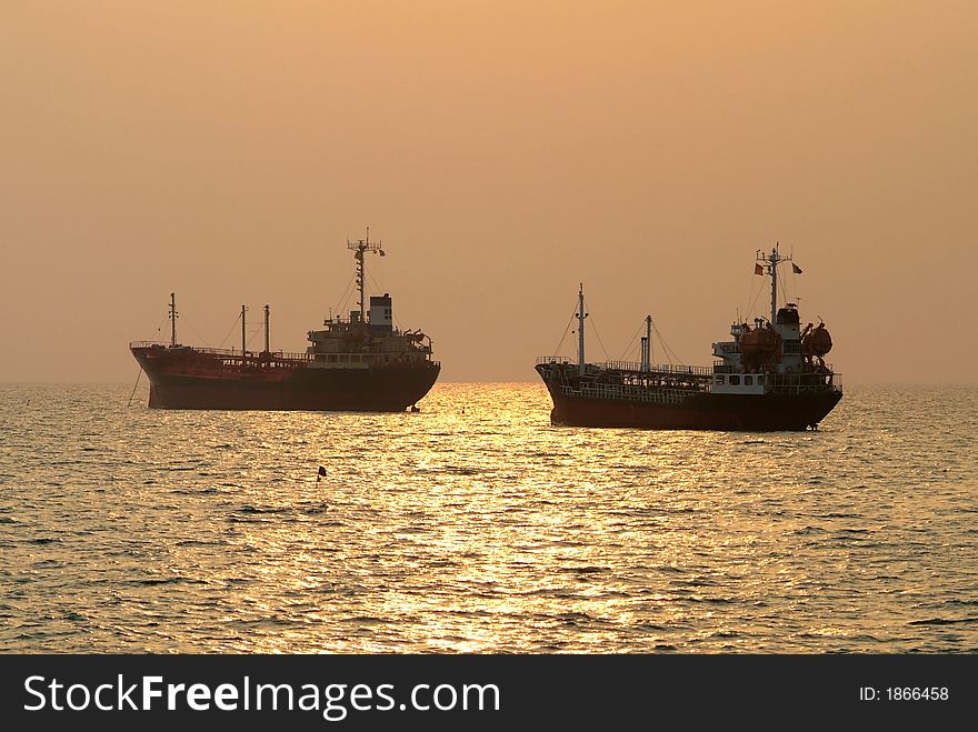 Two ships at anchor under the golden, tropical afternoon sun