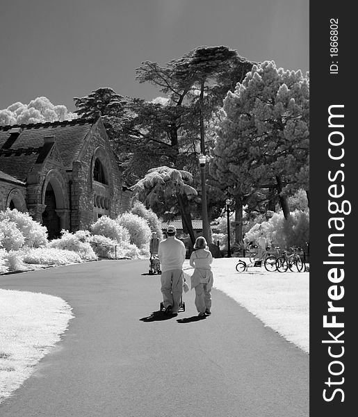 Young parents pushing stroller through city park infrared black and white. Young parents pushing stroller through city park infrared black and white.