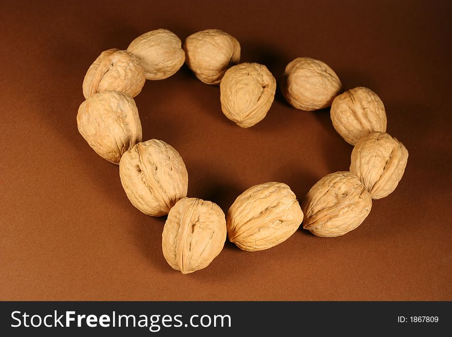 Heart made from walnuts on a brown background.