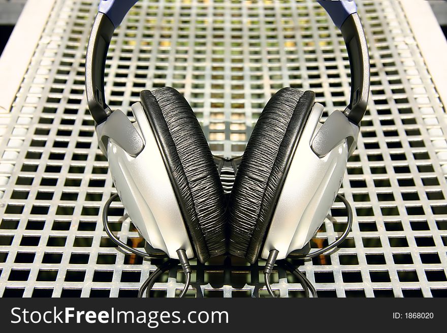 Symmetrical silver headphones on silver grid background