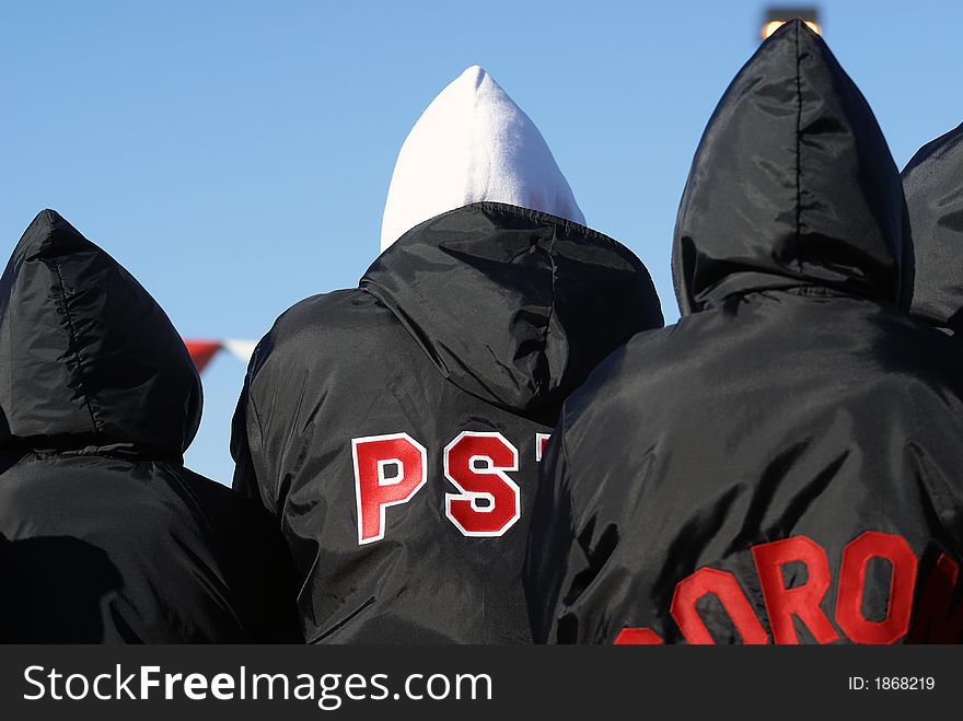 Kids in black parkas and swim caps with their backs to camera and blue sky. Kids in black parkas and swim caps with their backs to camera and blue sky.