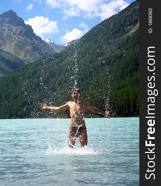 A young man is taking bath in a mountain lake Kucherlinskoe,temperature is 8-9 degrees centigrade. A young man is taking bath in a mountain lake Kucherlinskoe,temperature is 8-9 degrees centigrade