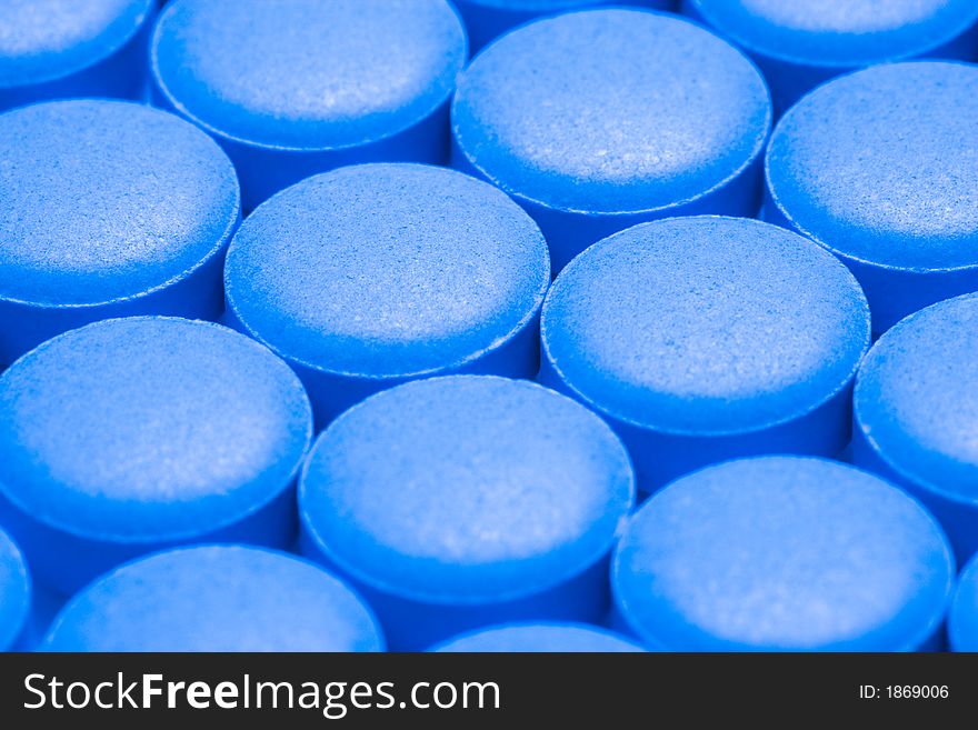 Round blue pills sit on a table.