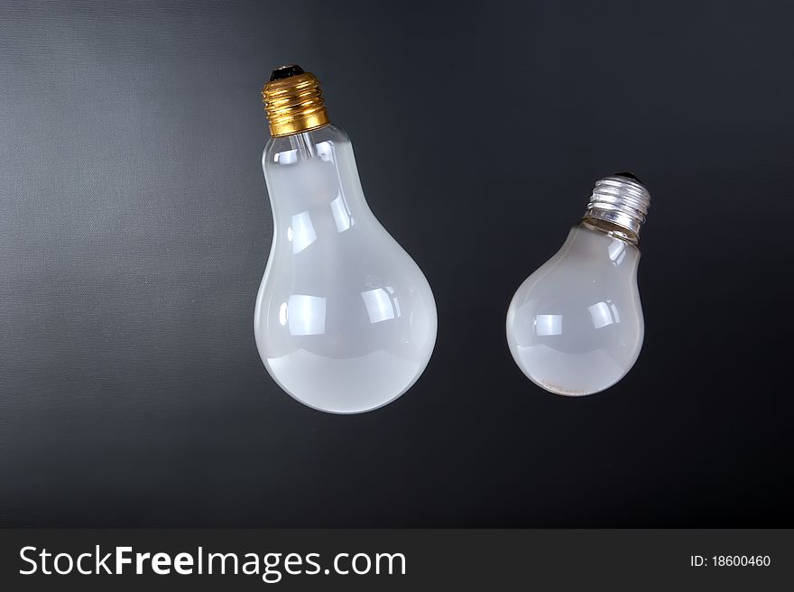 Large brushed electric incandescent lamps, against a dark background