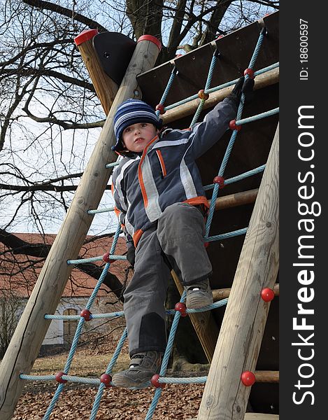 Young child standing on a rope ladder, having fun on a playground. Young child standing on a rope ladder, having fun on a playground