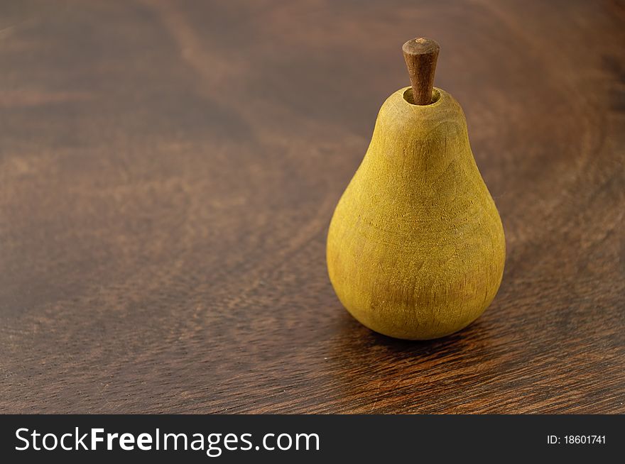 A wooden pear on dark wooden surface