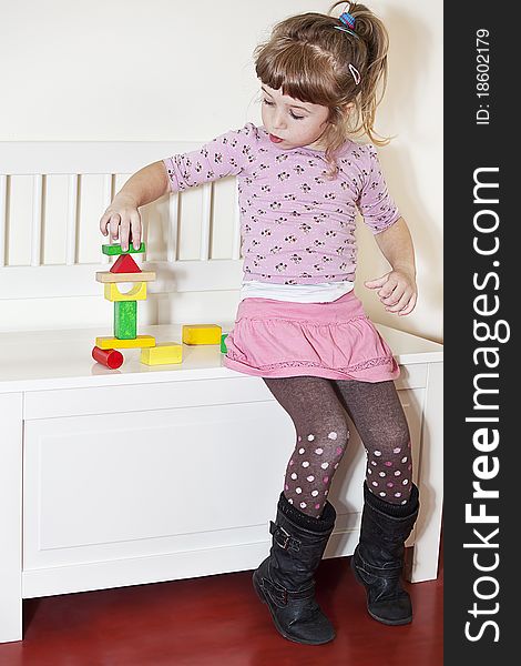 Little girl balancing colorful wooden blocks. Little girl balancing colorful wooden blocks