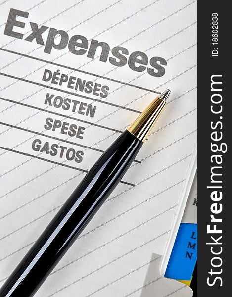 Expenses book page or record and a ball pen, shown as working on expenses, cost, saving, charge, payout, consumption, purchasing and other related business concept. Expenses book page or record and a ball pen, shown as working on expenses, cost, saving, charge, payout, consumption, purchasing and other related business concept.