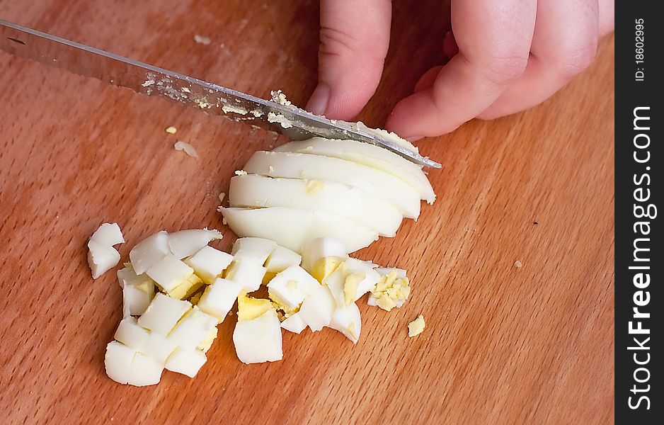 Sliced egg with knife on a wooden background