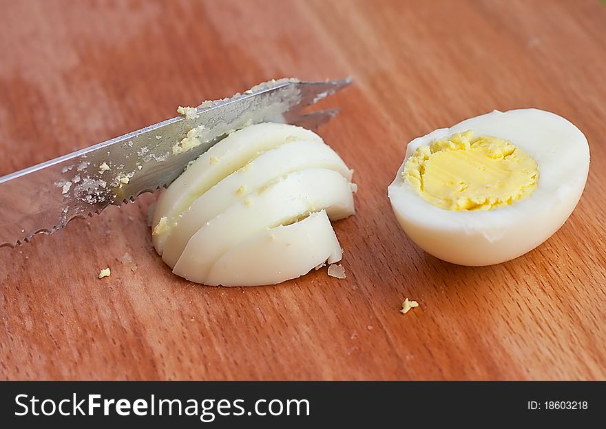 Sliced egg with knife on a wooden background