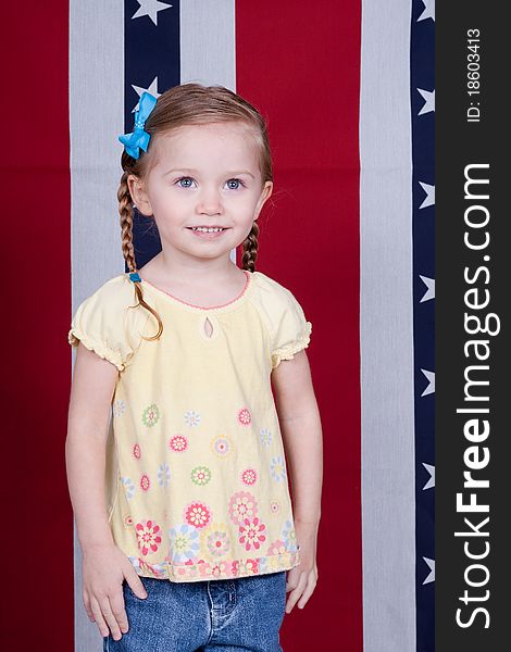 A happy American Girl standing in front of a red, white and blue background with stars.