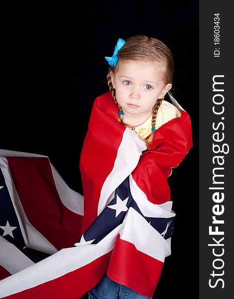 Girl with a confused look on her face. She is drapped in a patriotic design. There is a black background. Girl with a confused look on her face. She is drapped in a patriotic design. There is a black background.