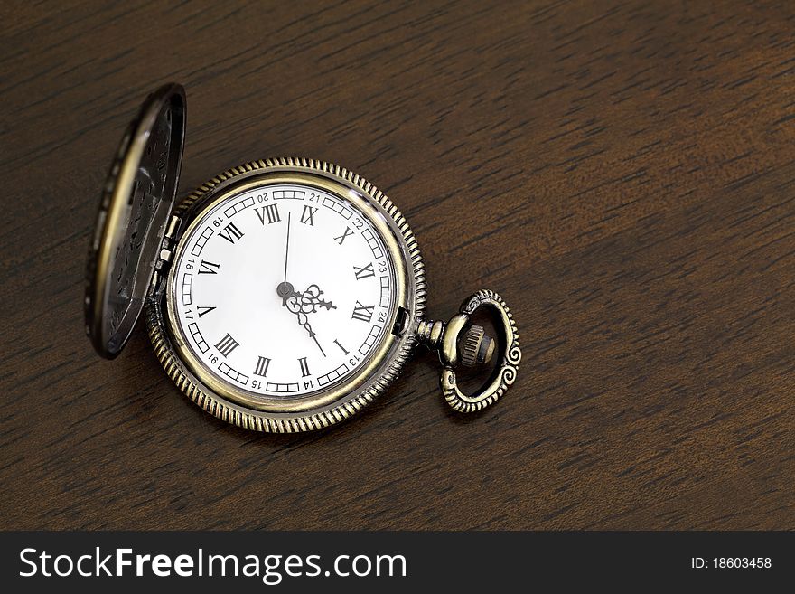 Antique pocket watch on a wood board