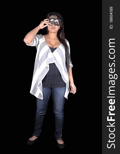 A beautiful Asian woman in jeans and a sweater standing for black background and holding a mask for her eyes. A beautiful Asian woman in jeans and a sweater standing for black background and holding a mask for her eyes.