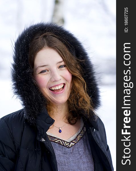 Laughing girl in the hood with fur in winter time