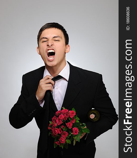 Handsome romantic young man holding rose flower and vine bottle prepared for a valentines day. gray background. Handsome romantic young man holding rose flower and vine bottle prepared for a valentines day. gray background