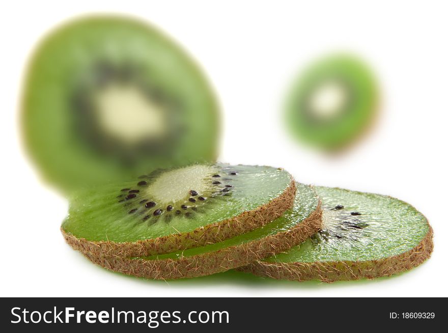 Close and low level capturing a selection of sliced and halved kiwi fruits with only the foreground slices in focus. White background. Close and low level capturing a selection of sliced and halved kiwi fruits with only the foreground slices in focus. White background.