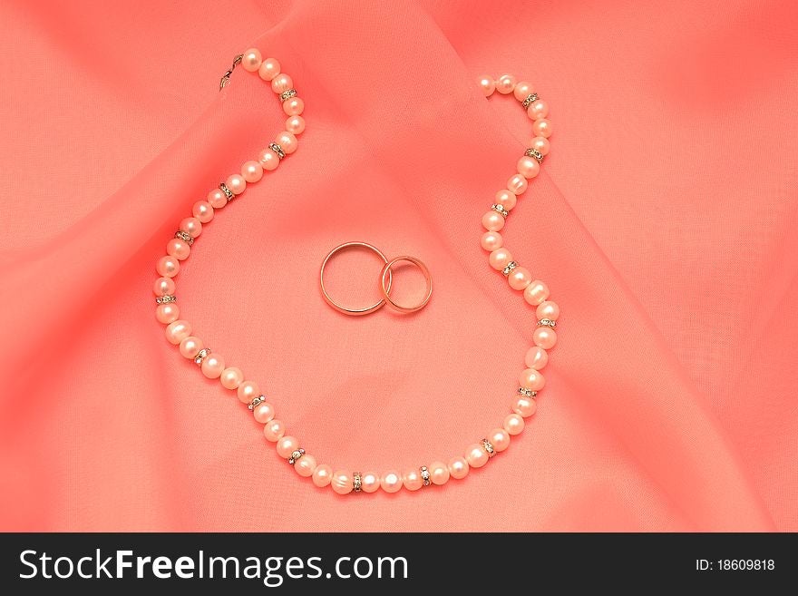 Photo of a silk fabric, pearls and rings. Photo of a silk fabric, pearls and rings