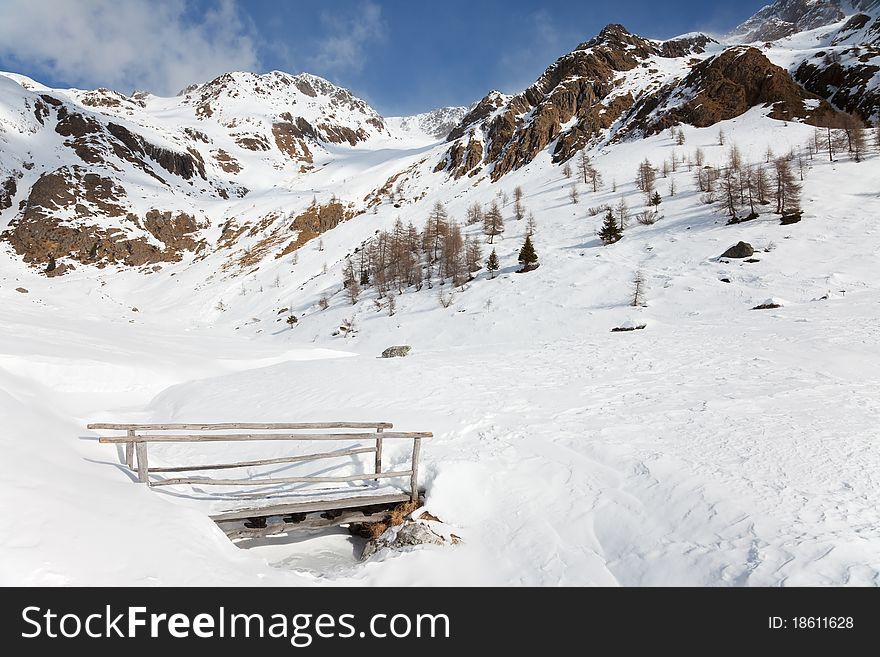 Wooden bridge on an icy torrent at the top of Caneâ€™s Valley during winter, before a snowfall. Brixia province, Lombardy region, Italy. Wooden bridge on an icy torrent at the top of Caneâ€™s Valley during winter, before a snowfall. Brixia province, Lombardy region, Italy