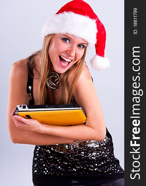 Pretty girl in Santa hat holding a laptop