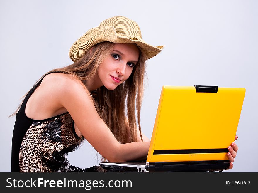 Attractive girl in a straw hat wth a yellow laptop