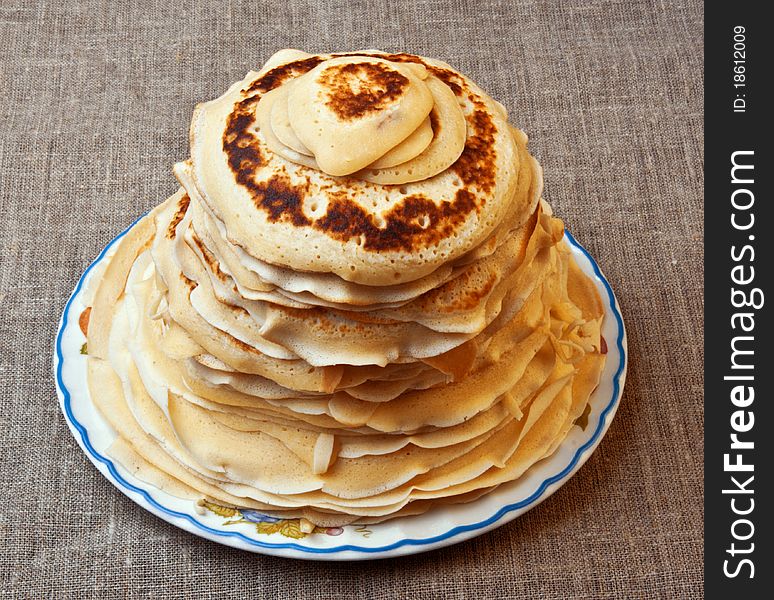 Pile of pancakes with an oil slice on a round plate
