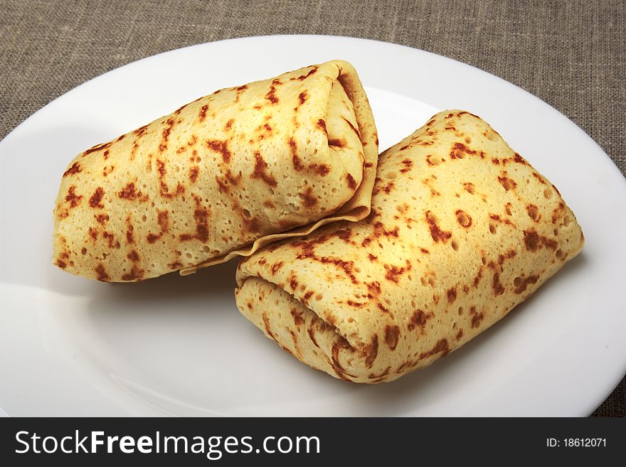 Pancakes with rolled up into a roll, on a white plate