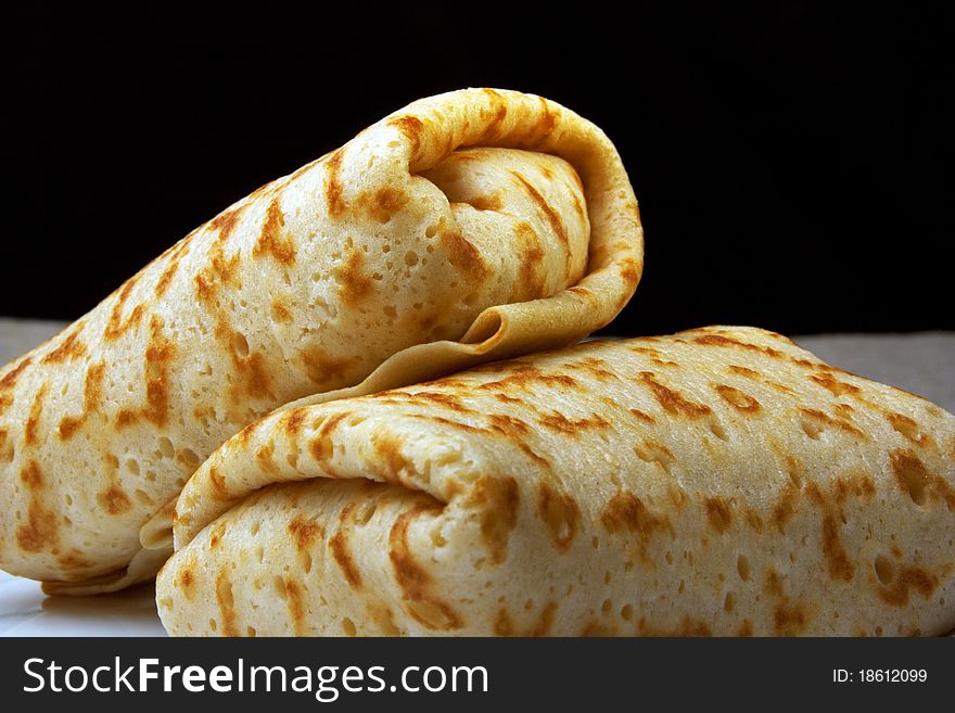 Pancakes with rolled up into a roll, folded in envelope, on a black