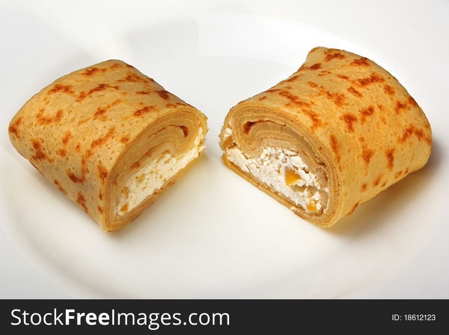 Pancakes with cottage cheese and dried apricots, rolled into rolls cut in half