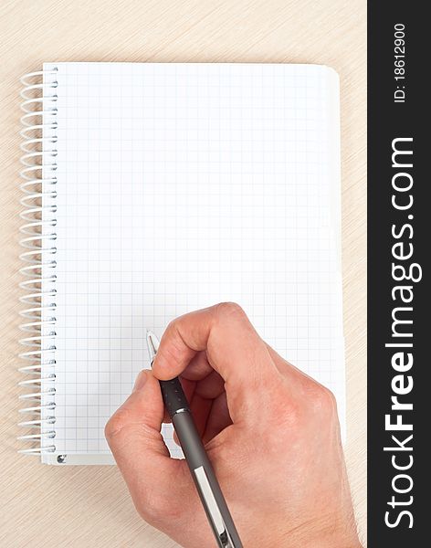 Male hand holding a pen writing notes in a notebook. Male hand holding a pen writing notes in a notebook.