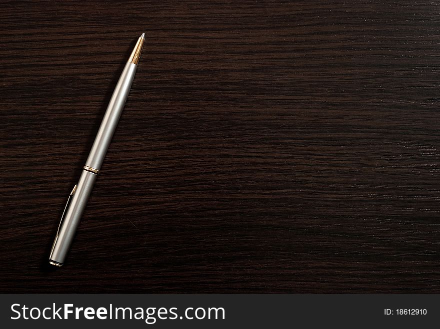 One silver pen on dark wood desk
