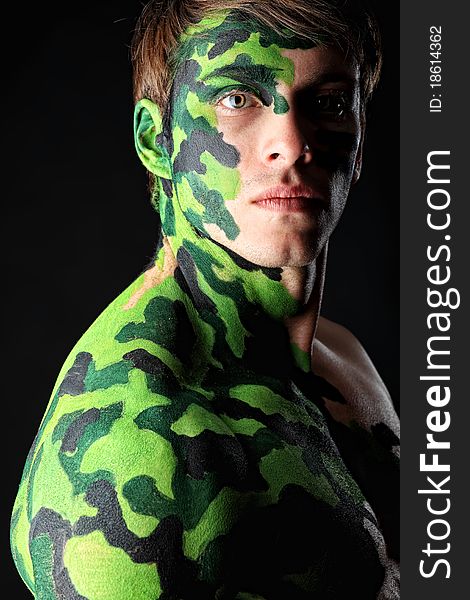 Shot of a conceptual soldier painted in khaki colors. Studio shot over black background.