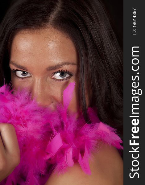 A woman is peaking out from behind a pink boa. A woman is peaking out from behind a pink boa.